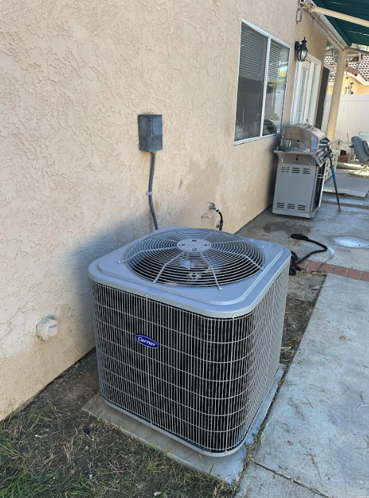 Outdoor central air conditioning condenser installed beside a home